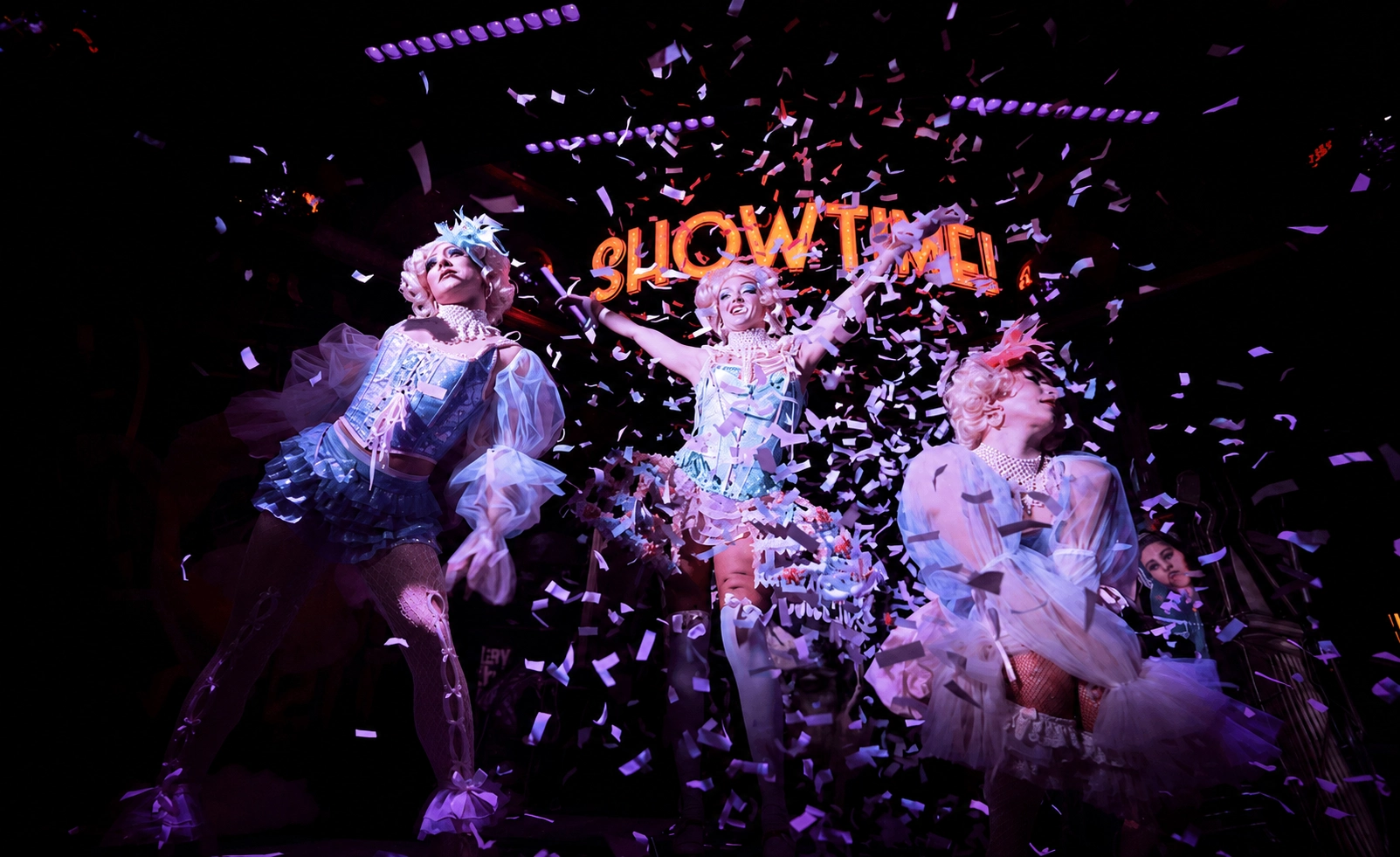 Costumed dancers celebrate on stage as confetti falls during a high-energy show.Costumed dancers celebrate on stage as confetti falls during a high-energy show.
